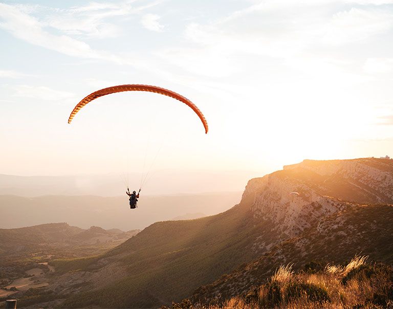  paraglider flying on mountains during sunset