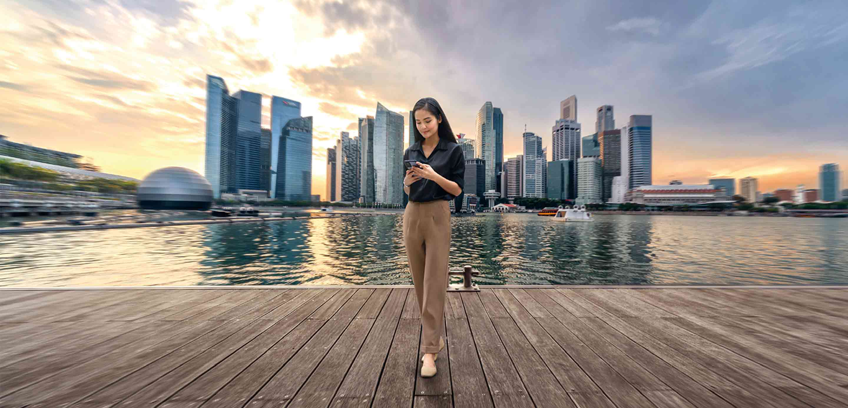 Woman standing at harbour front in Singapore using mobile phone